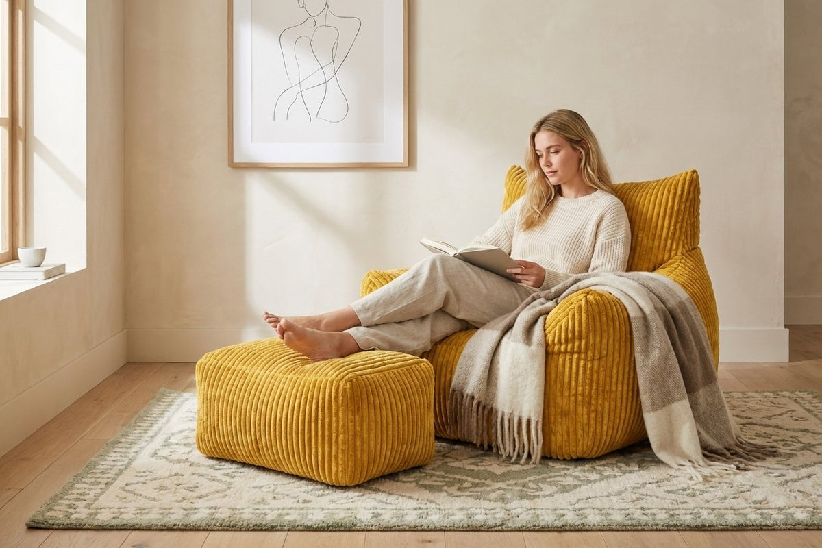 Lecture dans le fauteuil pouf Pola moutarde, pieds sur l'ottoman