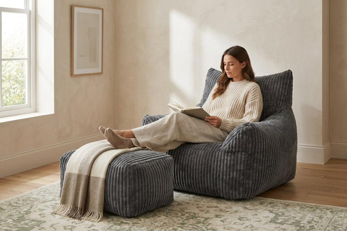 Lecture dans le fauteuil pouf Pola gris anthracite, pieds sur l'ottoman
