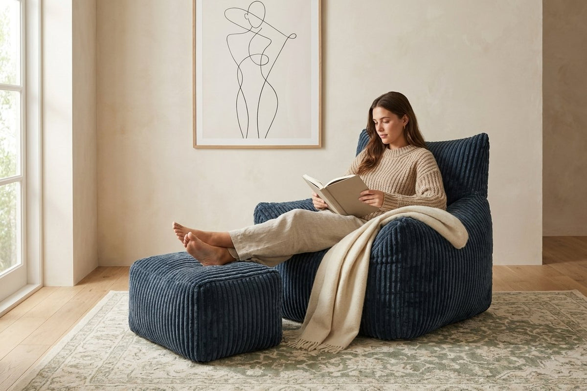 Lecture dans le fauteuil pouf Pola bleu nuit, pieds sur l'ottoman