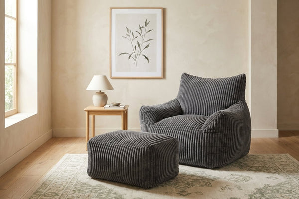 Fauteuil pouf Pola gris anthracite avec ottoman dans un salon lumineux